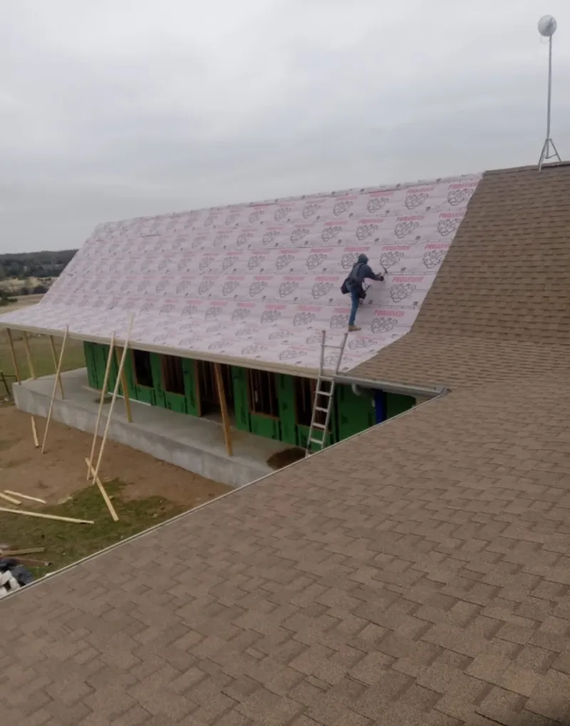 Worker preparing underlayment for a metal roof installation in Mayo